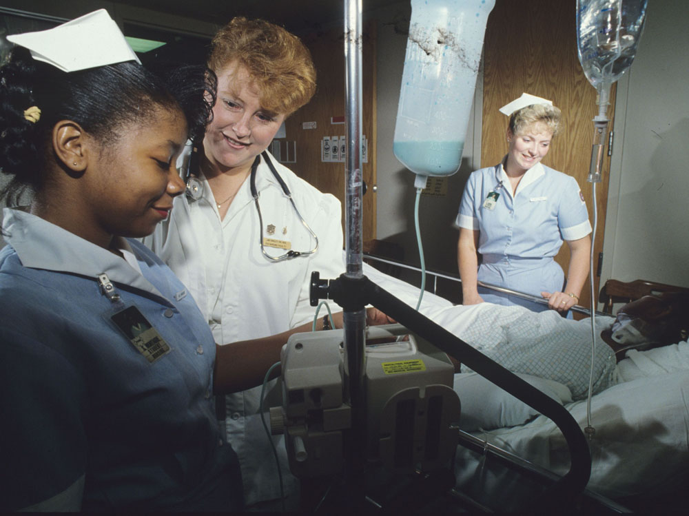 Two nursing students and an instructor with a patient